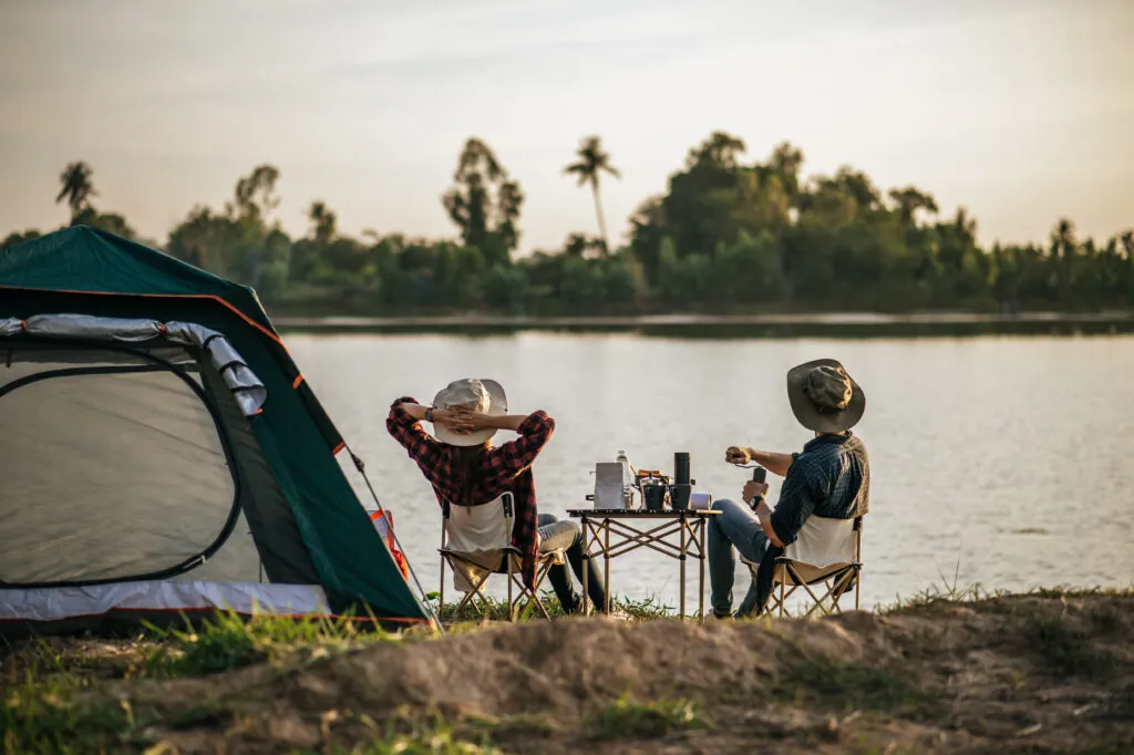 Cheerful Young Couples camping with morning coffee.